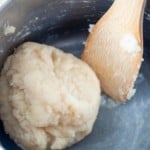 Pan with wooden spoon and churros dough in a ball.