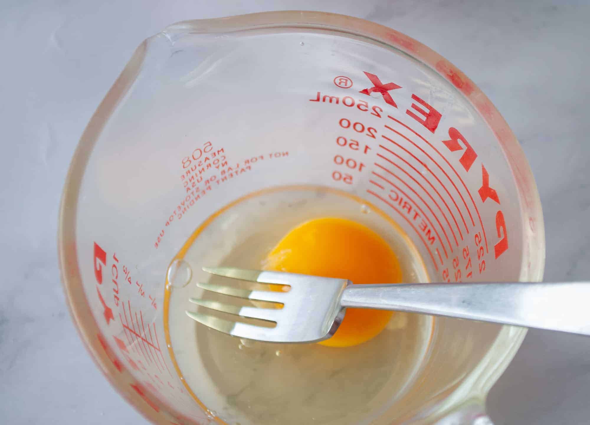 One egg and a fork in a measuring cup.