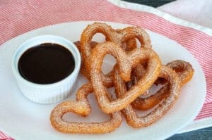 Plate with chocolate dipping sauce and heart shaped churros.