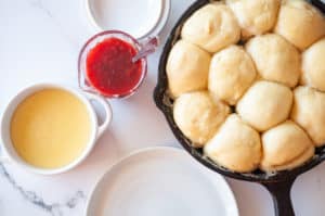 A skillet of freshly steamed Dampfnudel served with plum sauce and creme Anglaise.