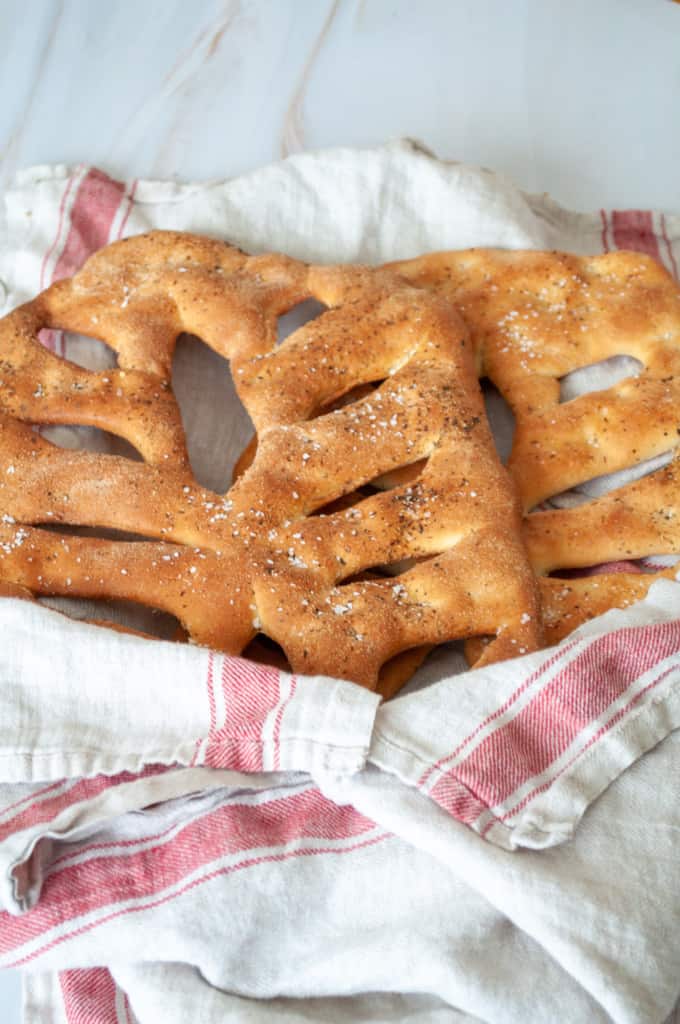 Two loaves of fougasse bread in a towel.