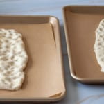 Two pieces of fougasse bread on baking sheets.