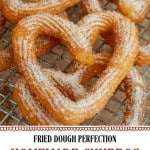 Close-up of sugar-dusted homemade churros on a cooling rack, with text promoting fried dough perfection and no trip out needed—discover how to make churros at home with this easy churro recipe.