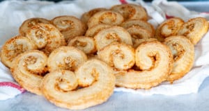 Freshly baked savory palmiers cooling on a kitchen cloth.