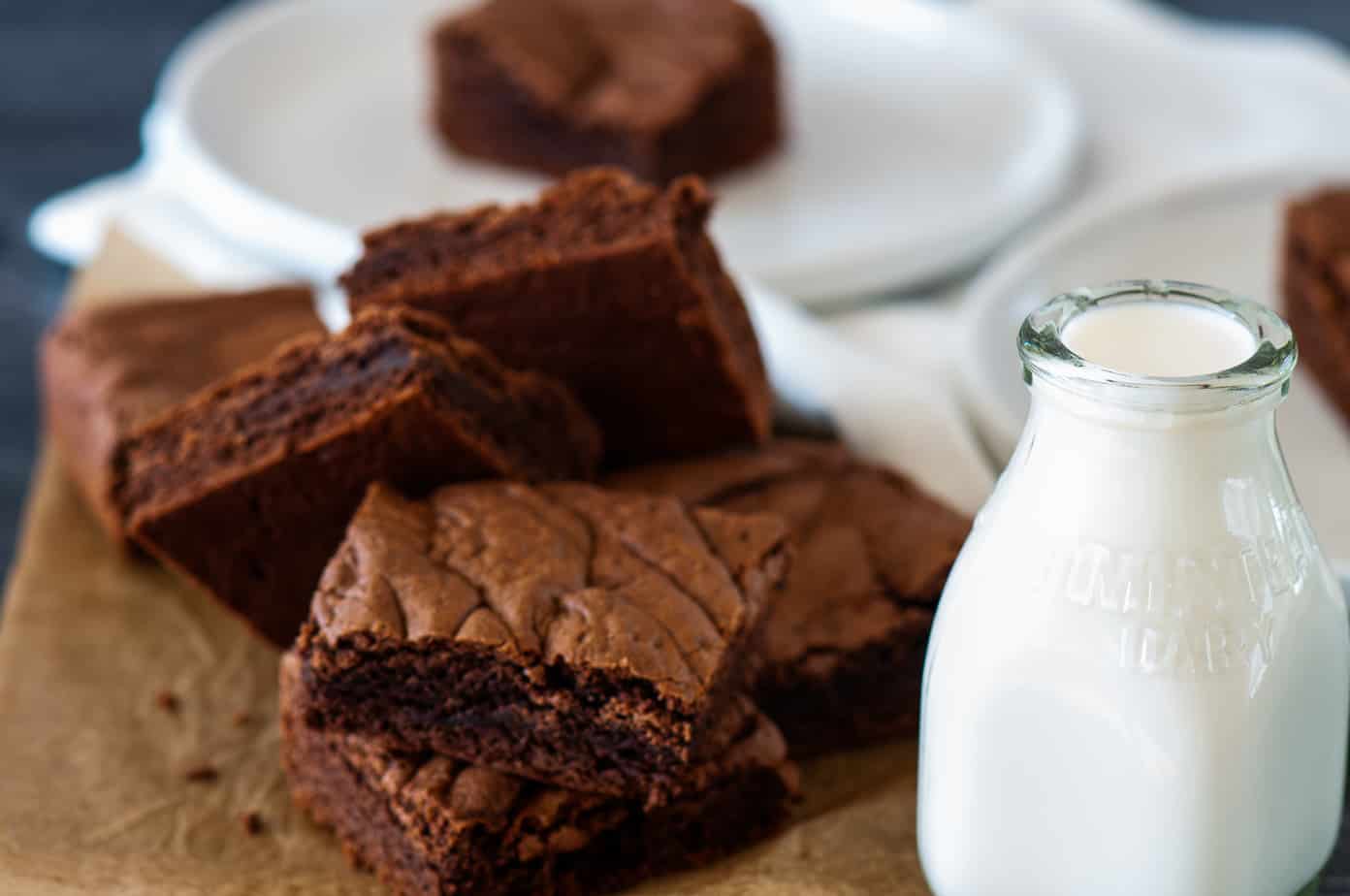 A stack of brownies and a milk bottle.