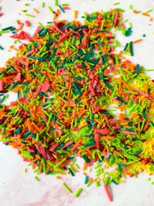Colorful DIY sprinkles scattered on a white surface.