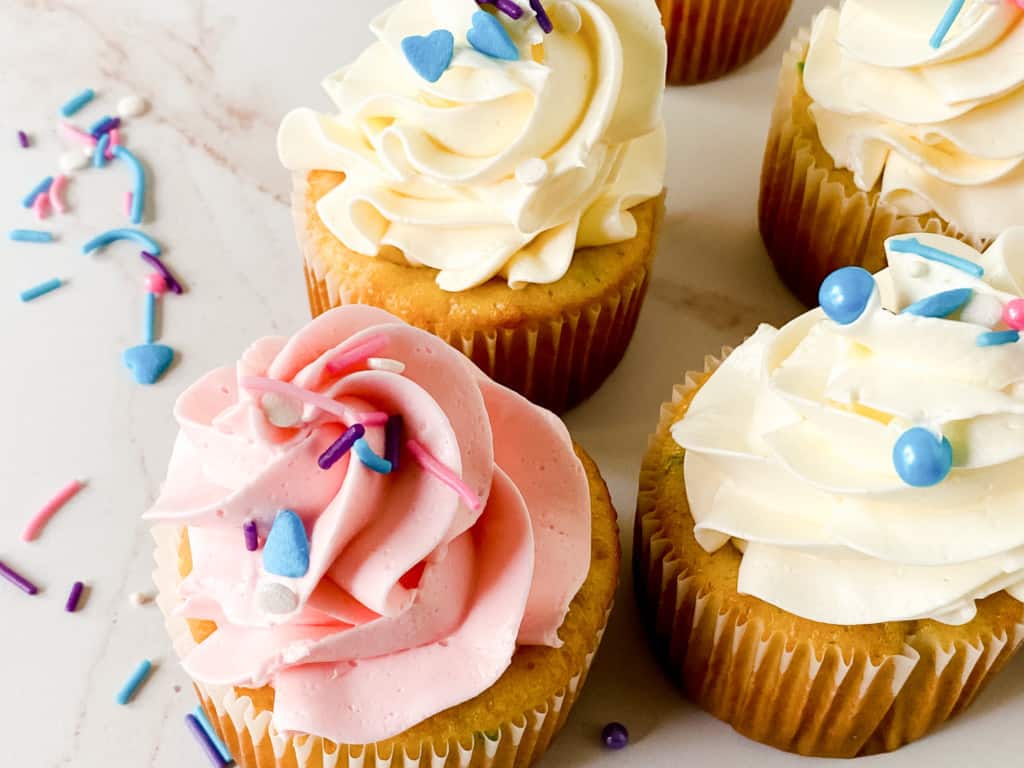 Three decorated cupcakes with creamy semi-homemade buttercream frosting and sprinkles.