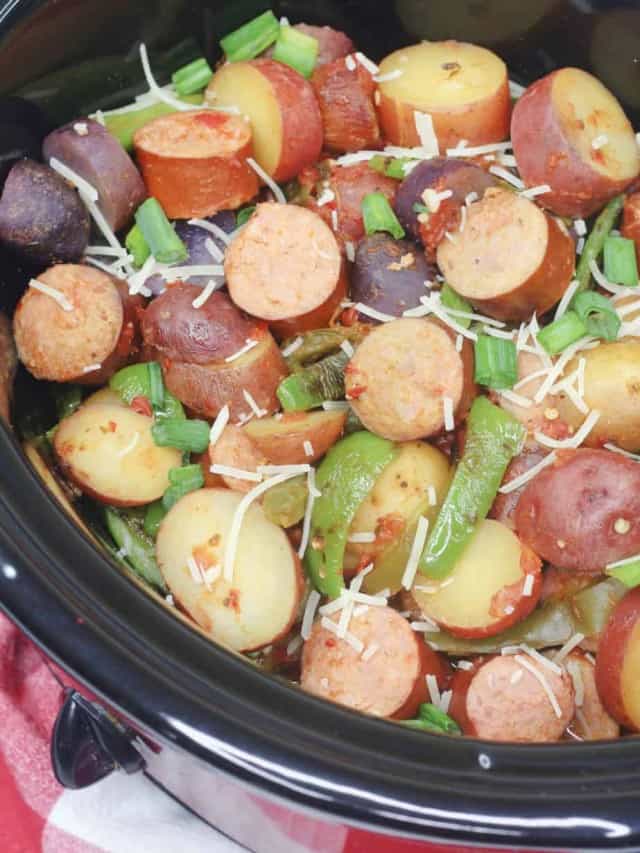 A crock pot filled with potatoes and sausages.