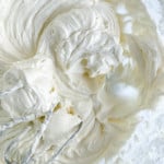 Whipped cream at a soft peak stage being mixed in a bowl for gingerbread cinnamon rolls.
