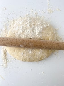 Ball of gingerbread dough with a rolling pin on top, ready for shaping into cinnamon rolls.