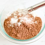 Mixing dry ingredients for Instant Pot Brownie Bites in a glass bowl with a whisk.