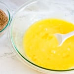 A bowl of melted butter and brown sugar sits on a marble countertop.