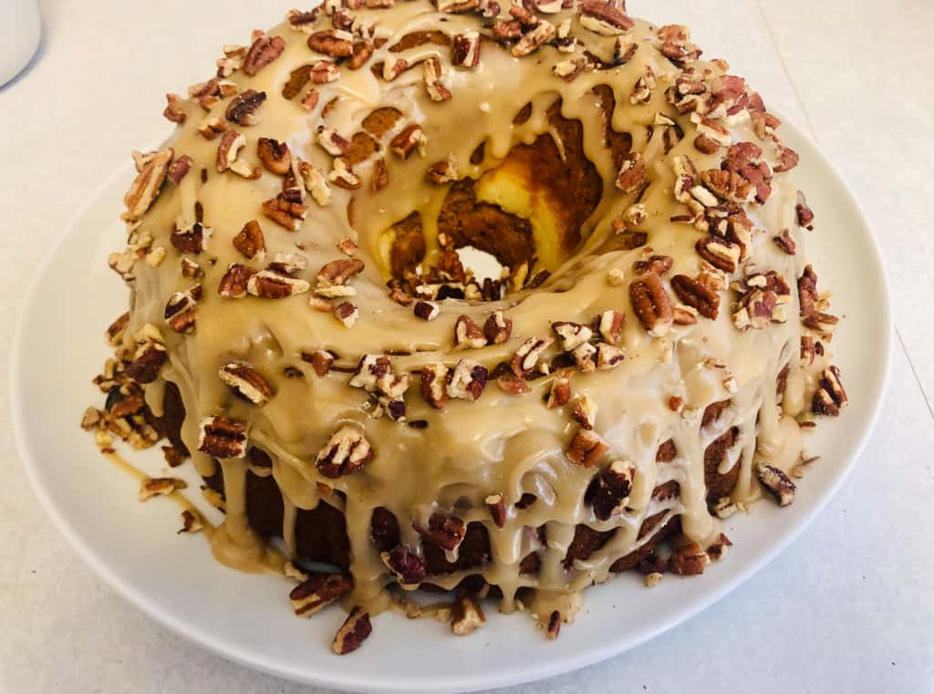 Pumpkin bundt cake drizzled with icing and topped with pecans.