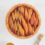 Easy freshly baked apple tart with glaze on a white surface next to a pastry brush.