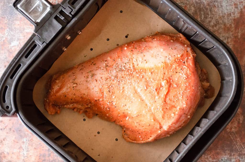 Turkey breast in an air fryer basket.