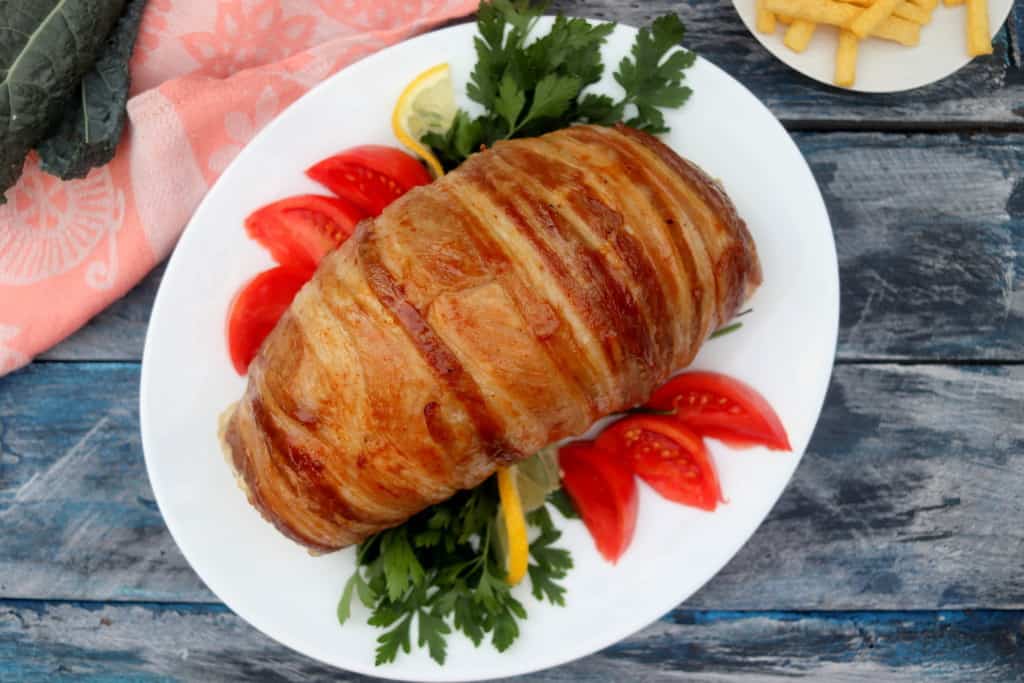 stuffed turkey breast with bacon wrapped around it.
