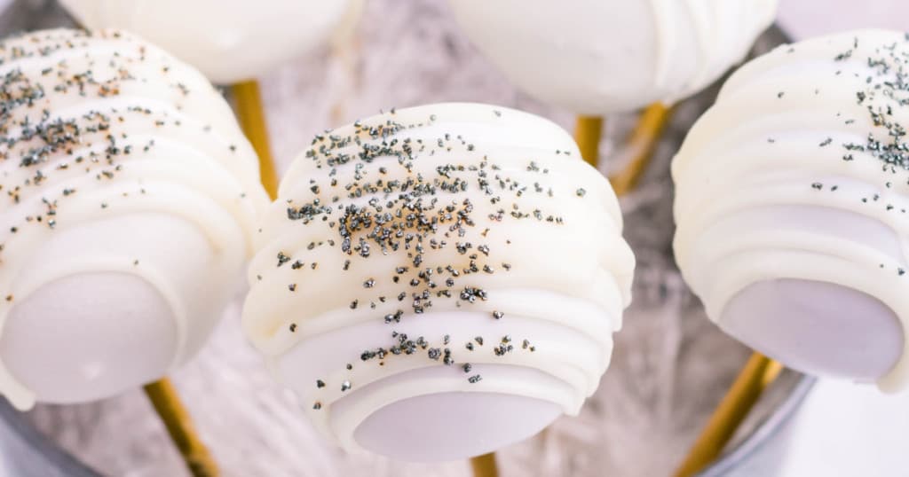 Gingerbread cake pops covered with white chocolate and sprinkled with black decorative sugar.
