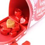 A red mailbox-shaped container with "Best Day Happy Valentine's Day" text, filled with red foil-wrapped heart-shaped candies, and one gold 'I Love You' marzipan heart on top.