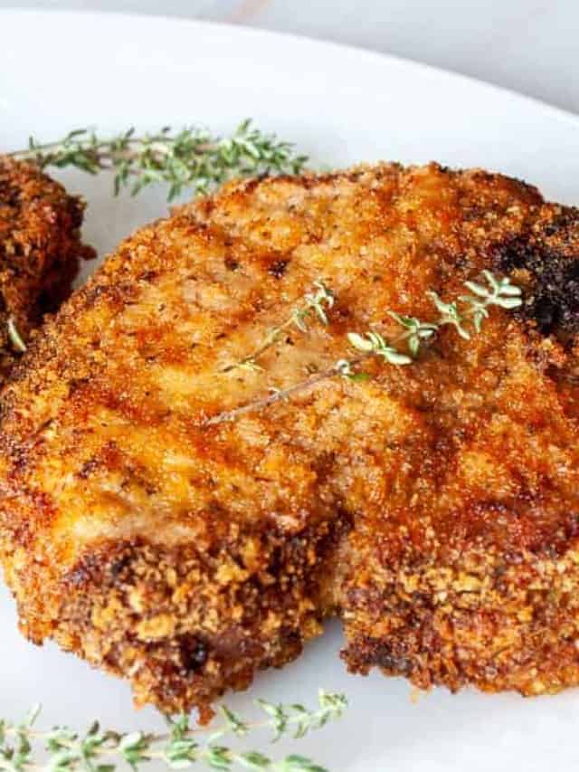 Pork chops on a white plate with sprigs of thyme.