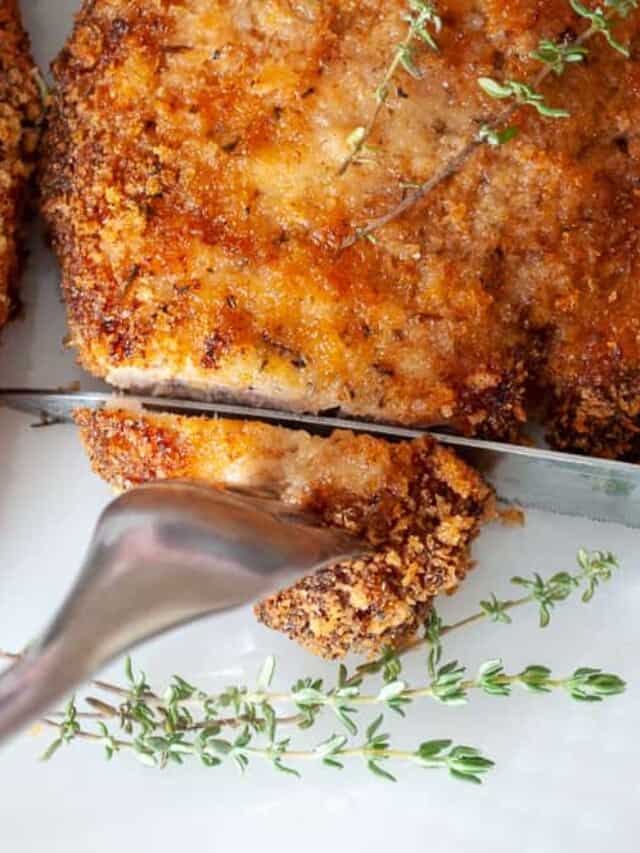 Pork chops on a plate with sprigs of thyme.
