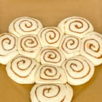 Cinnamon rolls arranged to form a heart shape on a parchment lined baking pan.