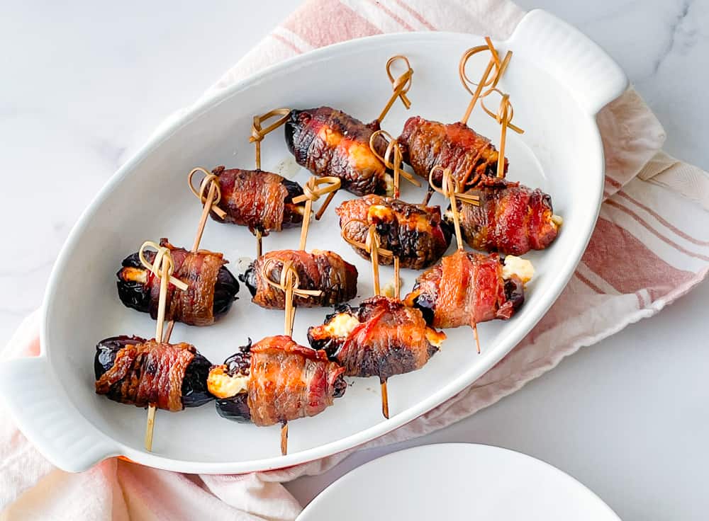 Air-fried bacon wrapped dates served on a white platter.