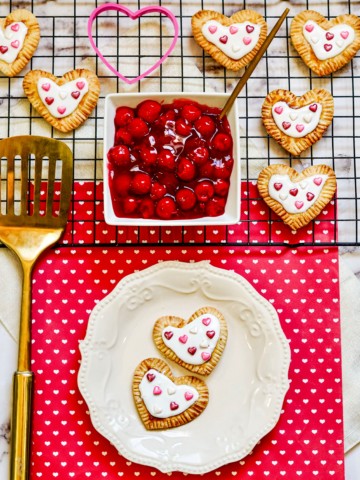 Pop-tarts on a cooling rack and plate with cherries and a spatula.