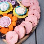 Sliced pink bagels arranged on a wooden board with different flavors of spread.