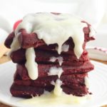 Stack of red velvet waffles with white chocolate dripping.