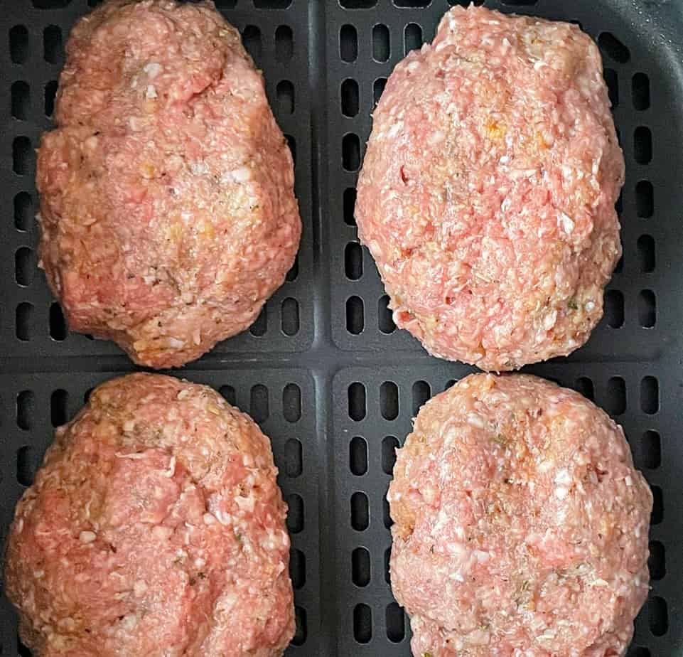 Uncooked meatloaves in the air fryer basket.