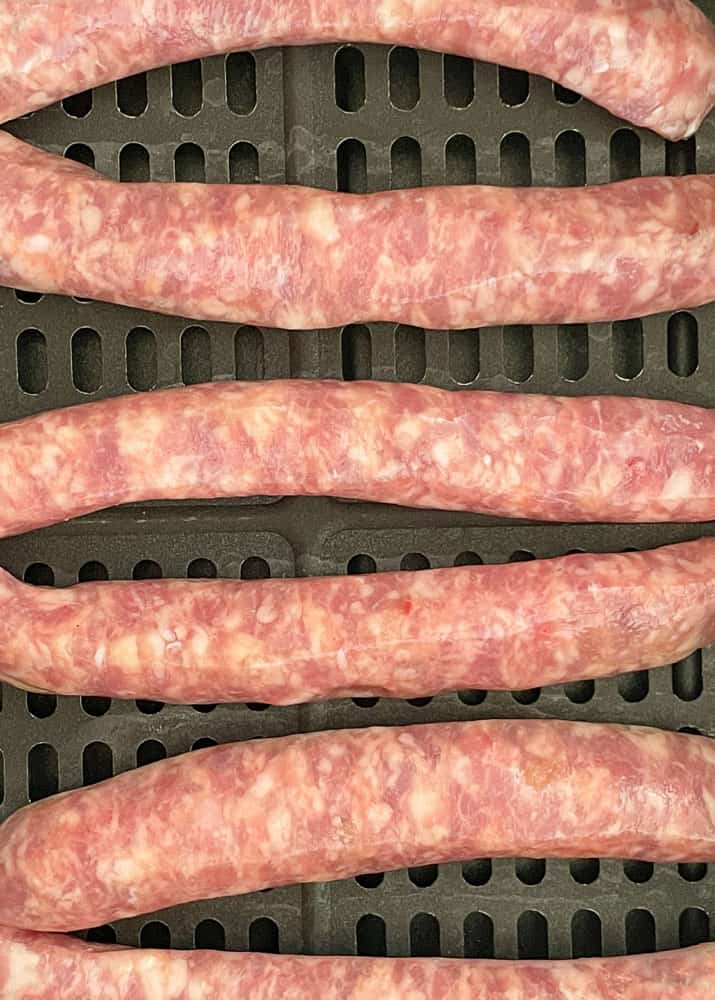Raw breakfast sausages in the basket of the air fryer.