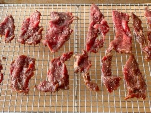 Sliced beef on a rack on a baking sheet.