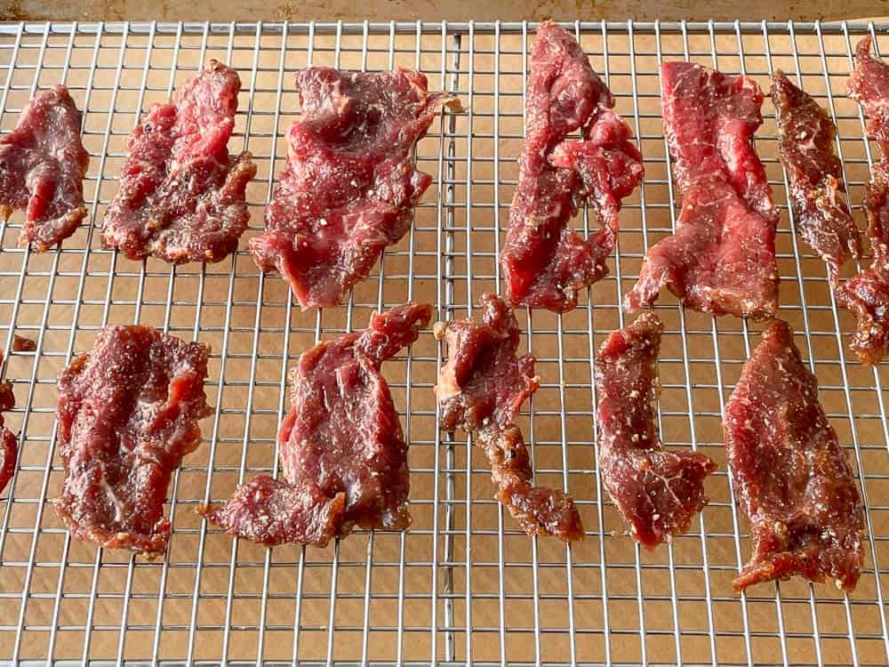 Sliced beef on a rack on a baking sheet.