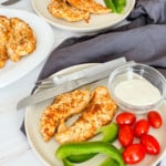 Air Fryer Grilled Chicken Tenderloins on plates, with vegetables, and dip.