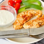 Air Fryer Chicken Tenders on a plate with dip, and fresh veggetables.