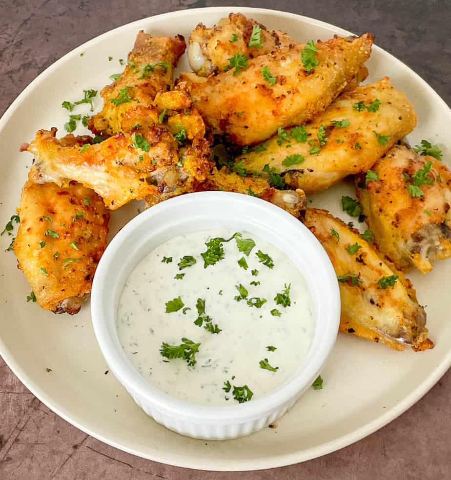 Crispy air fried lemon pepper wings served with a dipping sauce on a plate.