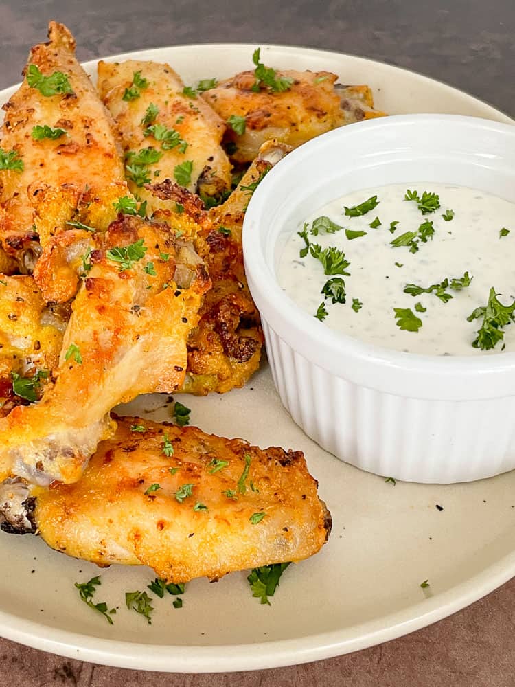 Lemon Pepper wings on a plate with dipping sauce.