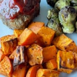 Air fryer roasted sweet potatoes, mini meatloaf, and brussles sprouts on a plate.