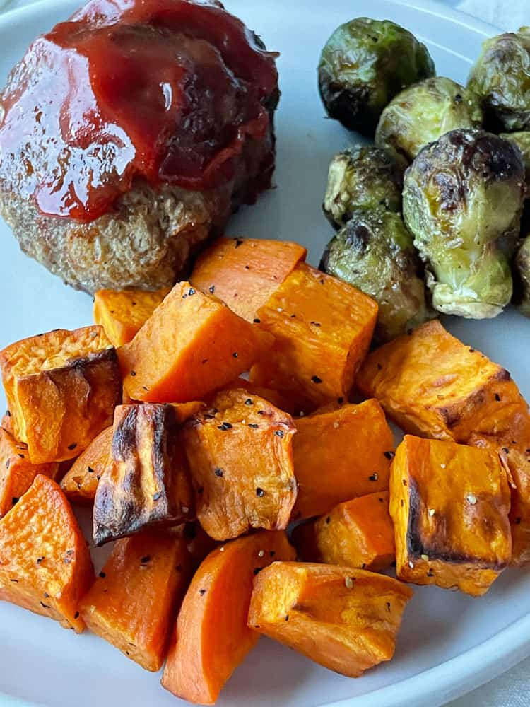 Air fryer roasted sweet potatoes, mini meatloaf, and brussles sprouts on a plate.