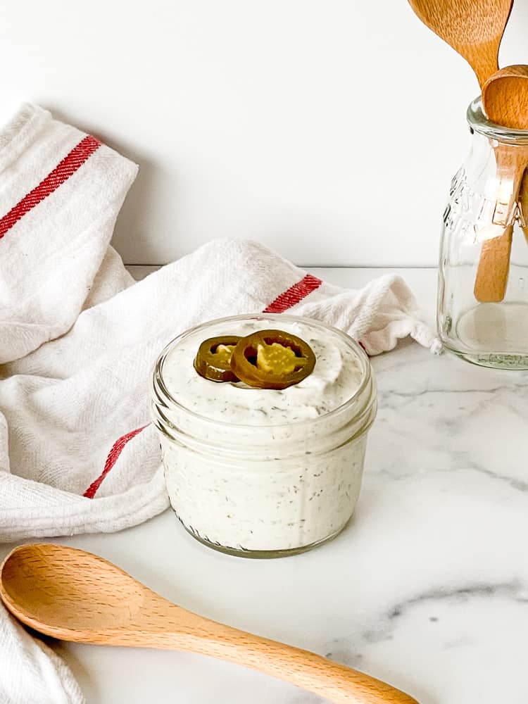 Spicy Jalapeño Ranch Dressing in a jar with a jalapeño slice on top.