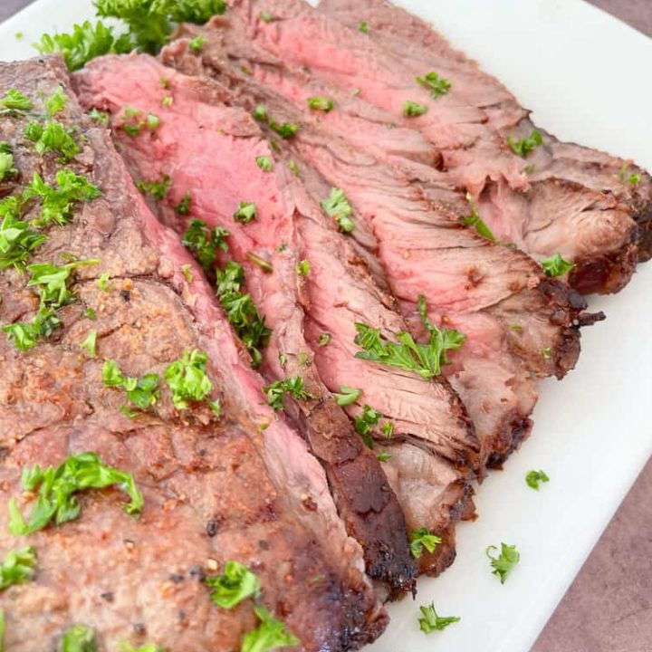 London Broil with parsley on a white plate.