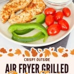 Plate with perfectly cooked Air Fryer Chicken Tenders, grape tomatoes, crisp green bell pepper slices, and a dish of creamy white dipping sauce. Fork and knife on the side. Text promoting “air fryer grilled chicken tenders.”.