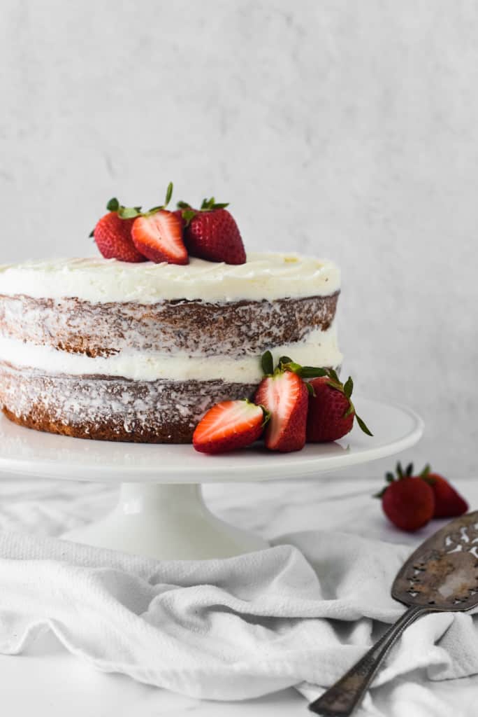 Fresh strawberry cake on a cake plate with fresh strawberries on top
