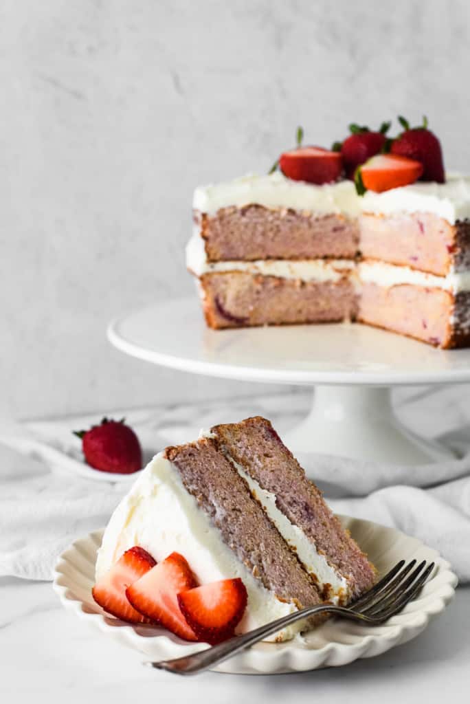 Fresh Strawberry Cake, with slices cut out of it, with fresh strawberries.
