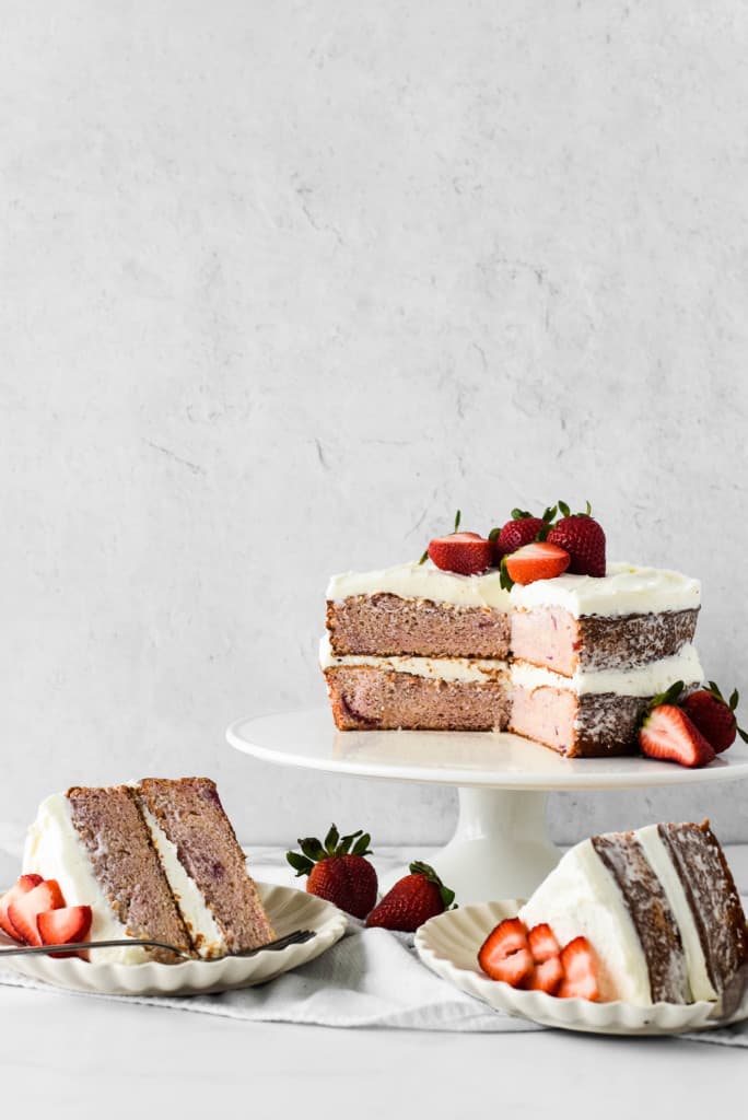 Sliced strawberry cake with berries on top.