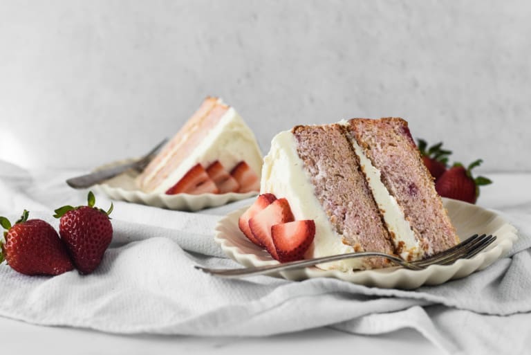 Pink strawberry cake sliced on plates.