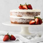 Naked frosted cake with berries on a cake plate.