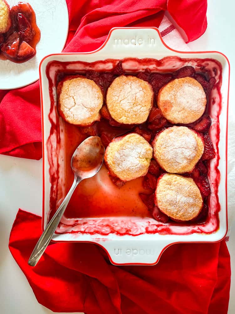 Serving up strawberry cobbler, a pan with a spoon, and a plate.
