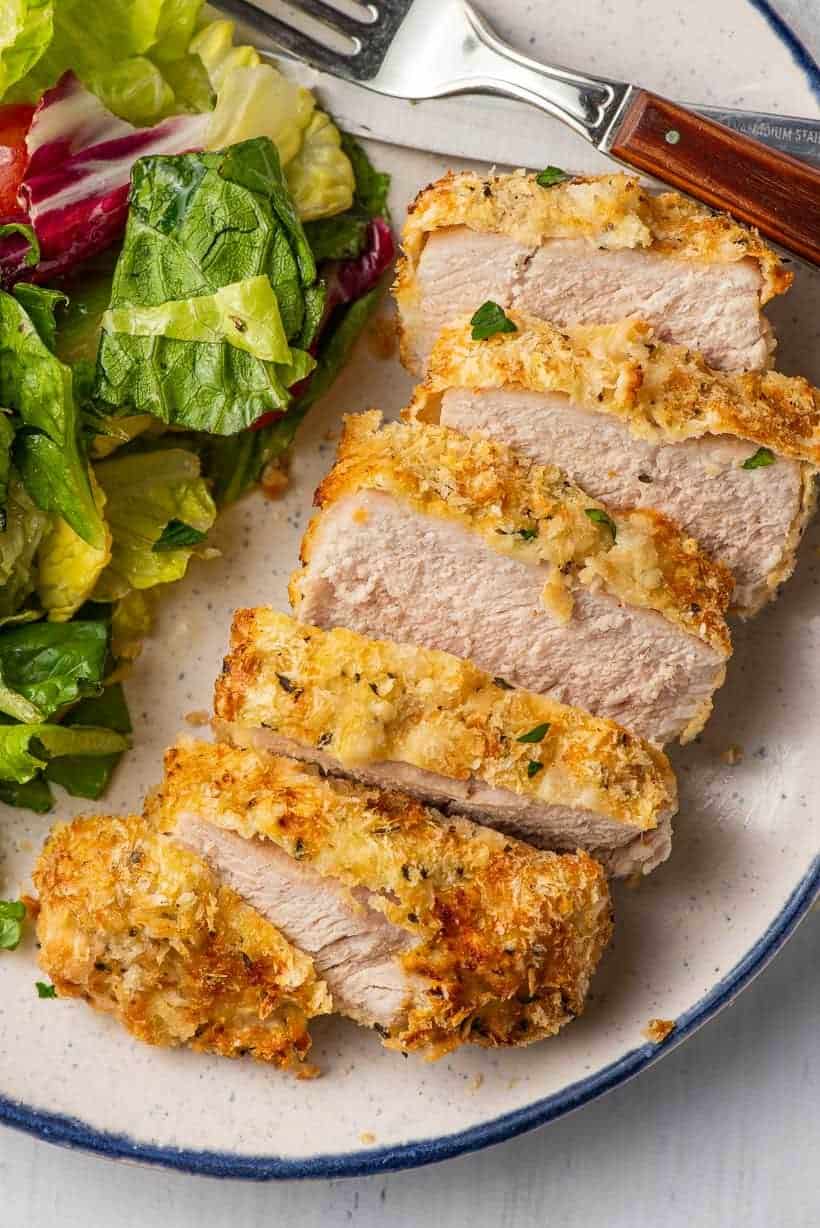 Slices of air-fried pork chops served with salad on a plate.