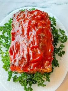 Easy Oven Meatloaf with parsley on a serving platter.